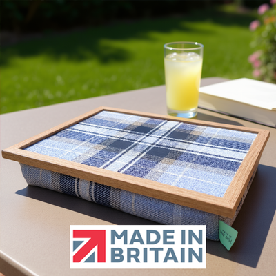 The Beagle lap tray, with a Made in Britain logo is displayed outdoors on a sunny table, featuring a wooden frame and cushioned base.