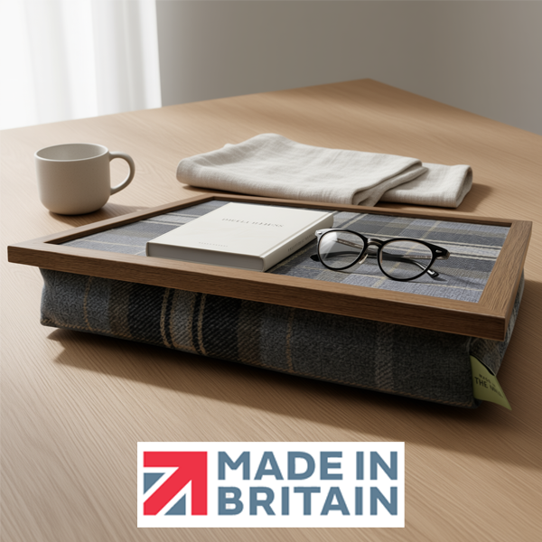 The Beagle lap tray with a wooden frame and cushioned base, shown with the Made in Britain logo on a wooden table. The lap tray has a book and some reading glasses on it
