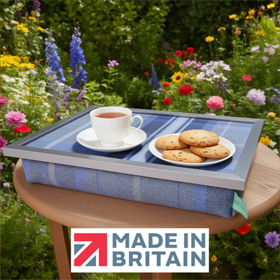 The Bernese lap tray with tea and biscuits on it, displayed outdoors in a colourful garden with the Made in Britain logo.