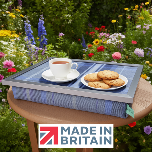 The Bernese lap tray with tea and biscuits on it, displayed outdoors in a colourful garden with the Made in Britain logo.