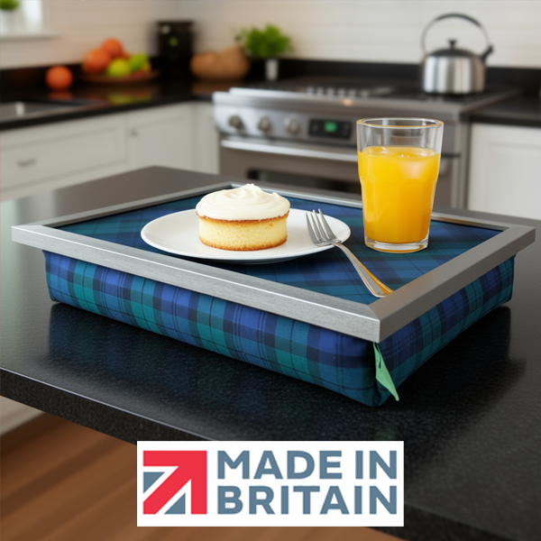 The Black Watch lap tray with silver frame and cushioned base on a kitchen counter top, styled with a plate with a scone and fork on and a glass of orange juice, alongside the Made in Britain logo.
