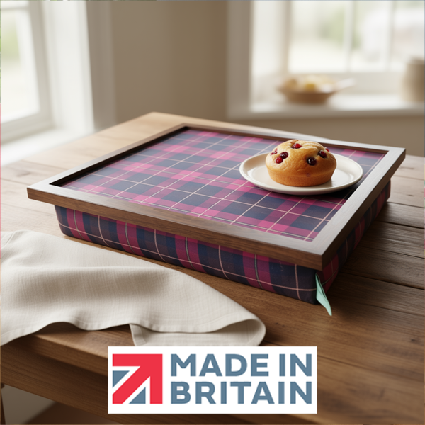 The Burgundy Boyd Tartan lap tray with wooden frame and a cushioned base, shown on a rustic table with a pastry, alongside the Made in Britain logo.