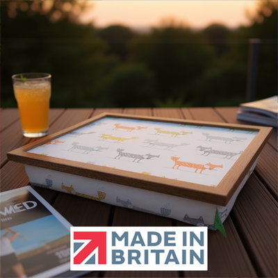 The Foxy lap tray with wooden frame and a cushioned base, shown outdoors at sunset, alongside the Made in Britain logo.