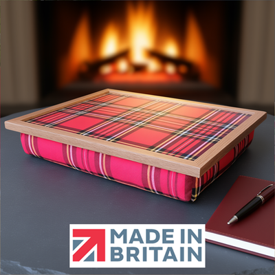 The Royal Stewart Red Tartan lap tray with wooden frame and a cushioned base, displayed by a cosy fireplace, alongside the Made in Britain logo.