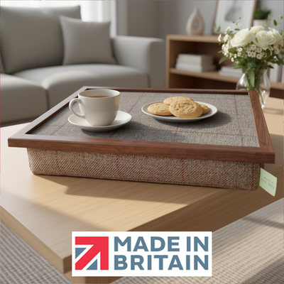 The Springer lap tray with a wooden frame and cushioned base, shown with the Made in Britain logo on a wooden table. The lap tray has a cup and some biscuits on it