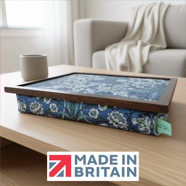 The William Morris Hyacinth lap tray with floral blue design and a wooden frame, displayed in a cosy living room, alongside the Made in Britain logo.